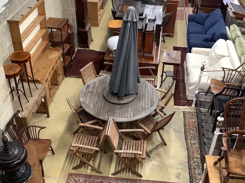 A circular teak garden table, 150cm diameter, height 74cm eight teak folding chairs, parasol and base (parasol rope is broken)